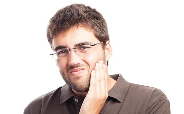 man holding his jaw considering alternatives to soda